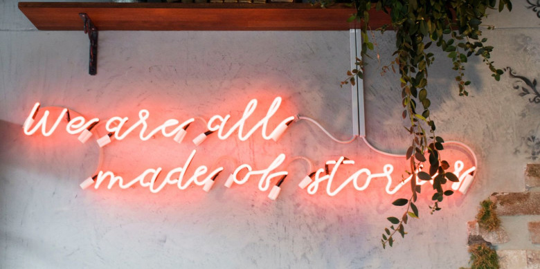 neon sign that says "we are all made of stories."